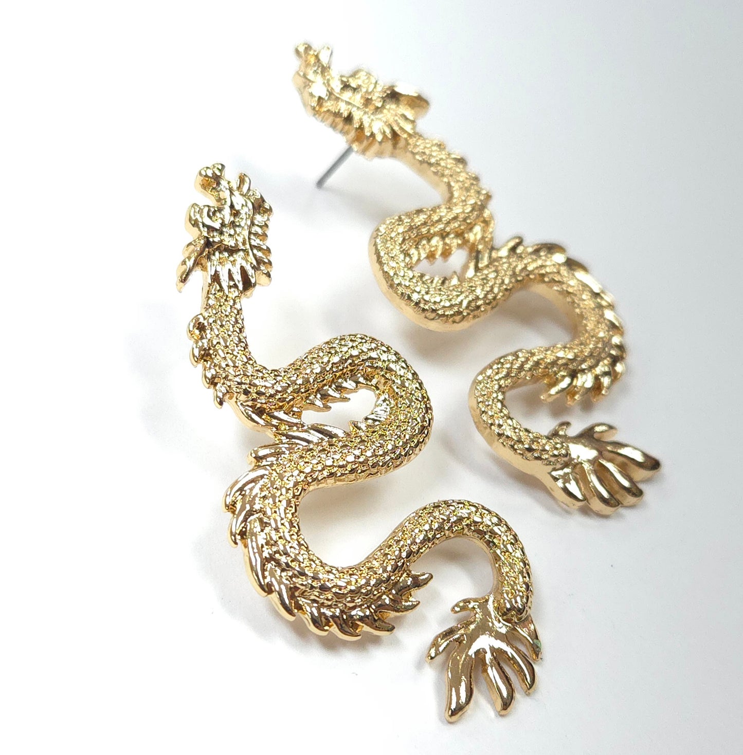 Gold dragon-shaped earrings on a white background