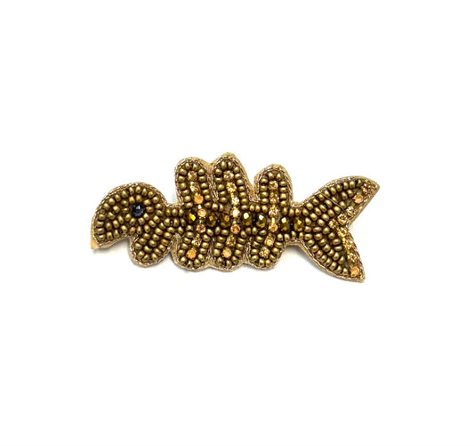 Gold fish-shaped brooch on a white background