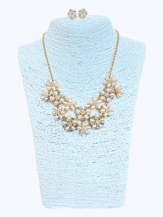 Elegant floral crystal bib necklace set with matching flower stud earrings featuring layered rhinestone petal clusters and gold-tone chain.