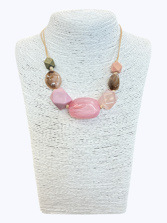 Pink statement bead necklace with glossy marbled resin accents and geometric details on neutral cord for a playful boutique-inspired look.