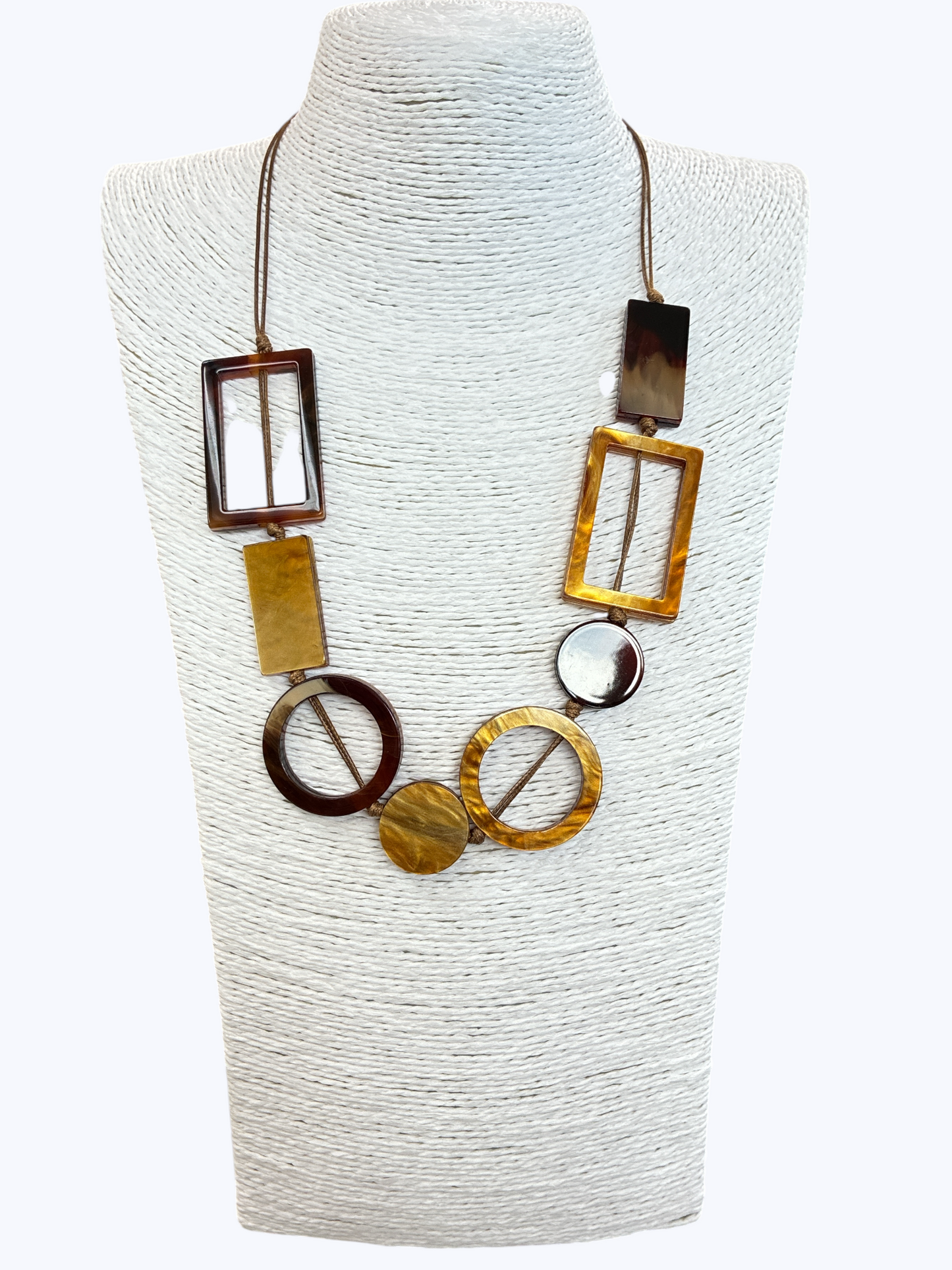 Geometric statement necklace with marbled amber resin shapes and open circle accents on brown cord for a modern boutique-inspired look.