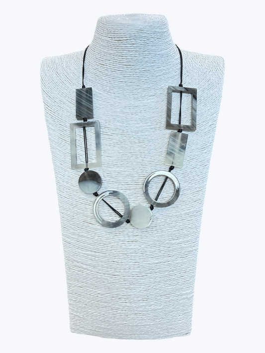 Geometric statement necklace with smoky gray marbled resin shapes and open circle accents on black cord for a modern boutique-inspired look.