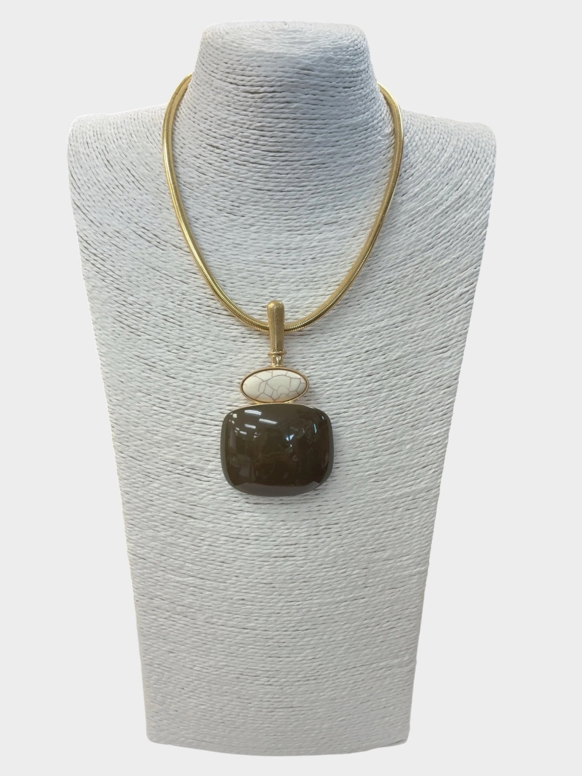 A gold chain necklace with a dark brown polished stone pendant and a small white oval accent, displayed on a textured light gray jewelry bust.