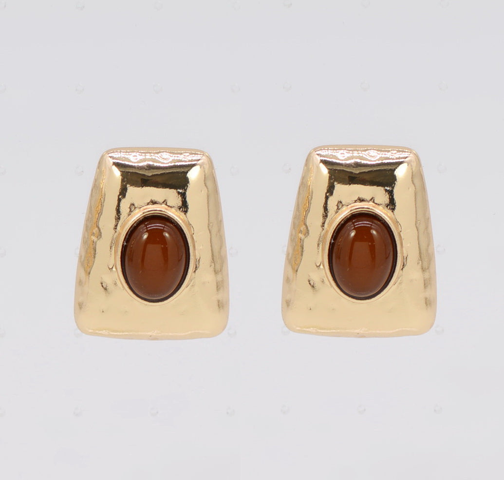 Gold earrings with brown gemstones on a light gray background
