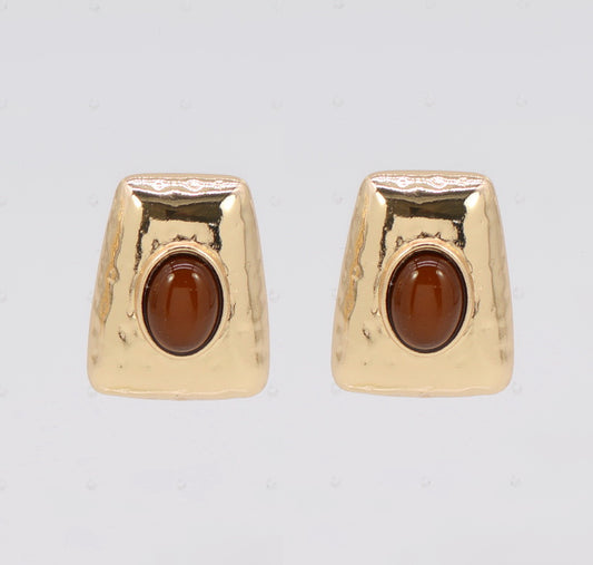 Gold earrings with brown gemstones on a light gray background