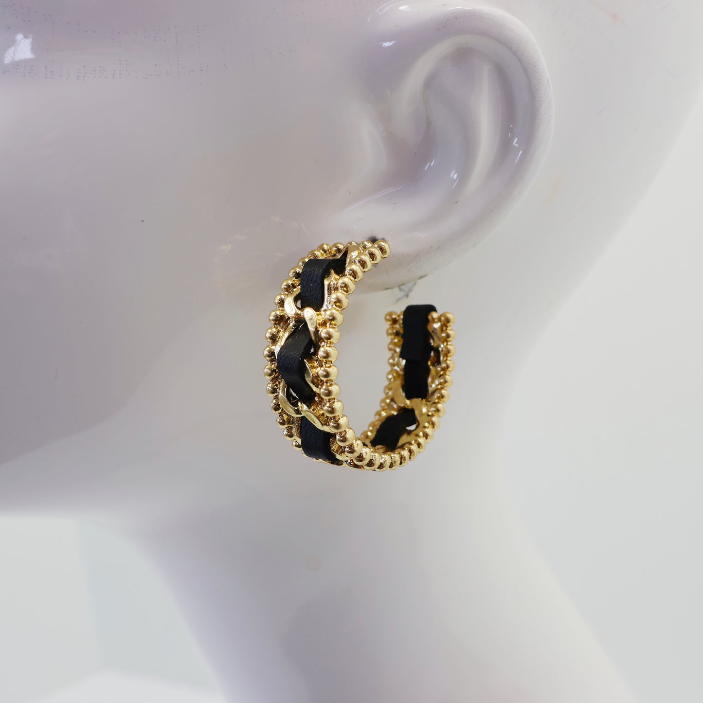 Braided chain hoop earrings with textured beaded edging and woven detail in a modern boutique fashion style.