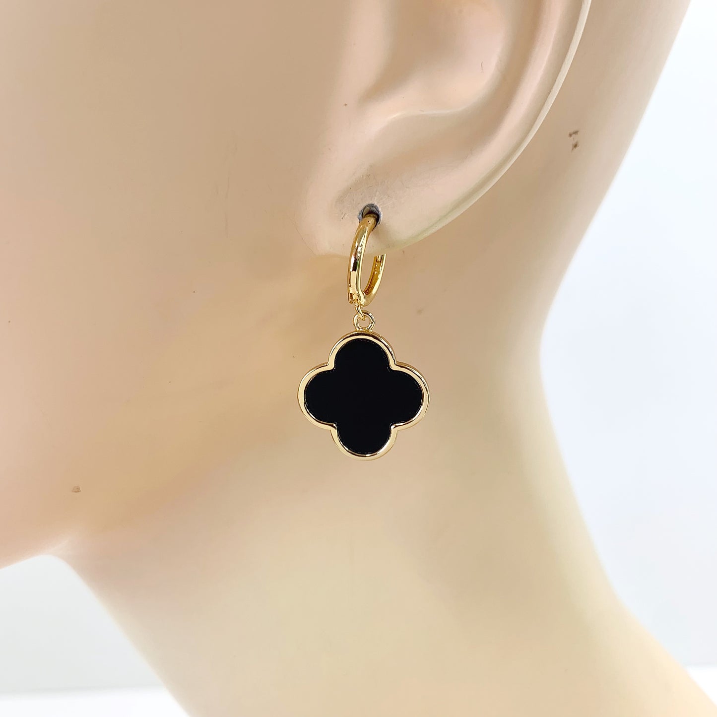Hoop earrings with clover-shaped drop charms and polished trim in a chic boutique fashion style.