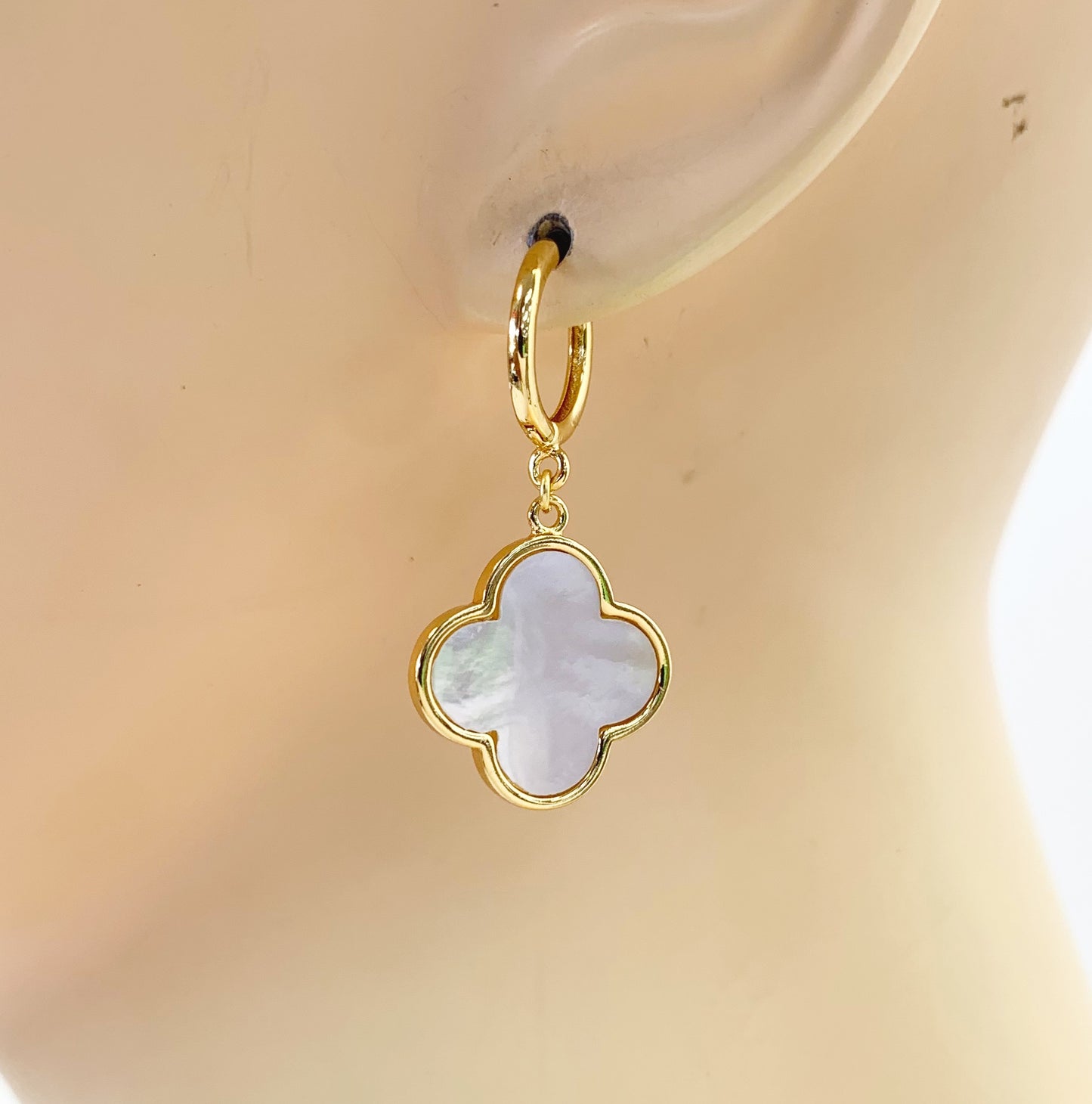 Hoop earrings with clover-shaped drop charms and polished trim in a chic boutique fashion style.