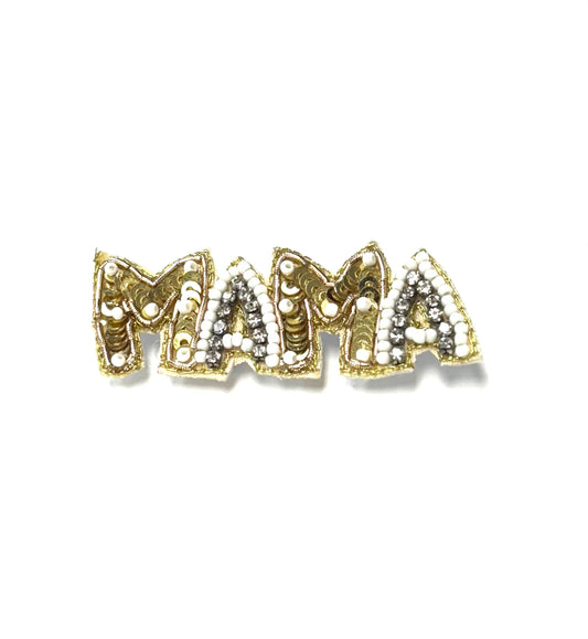 Gold and silver 'MAMA' brooch on a white background