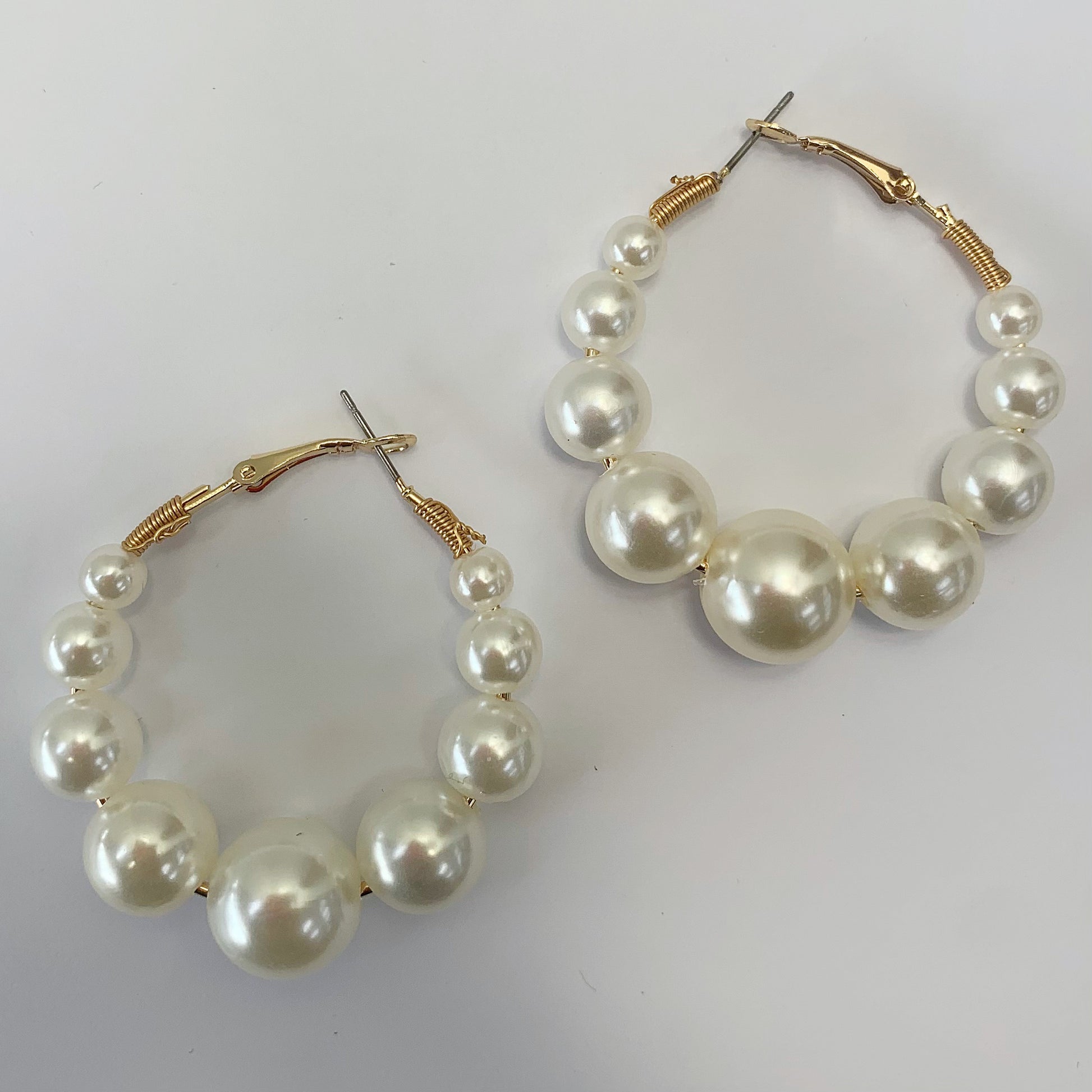 Oversized hoop earrings with graduated faux pearl accents in a glamorous boutique fashion style.