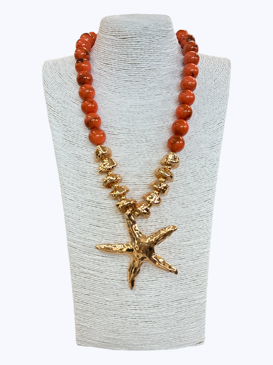 Coastal boutique necklace featuring coral-style round beads, textured metallic accent beads, and oversized starfish pendant centerpiece.
