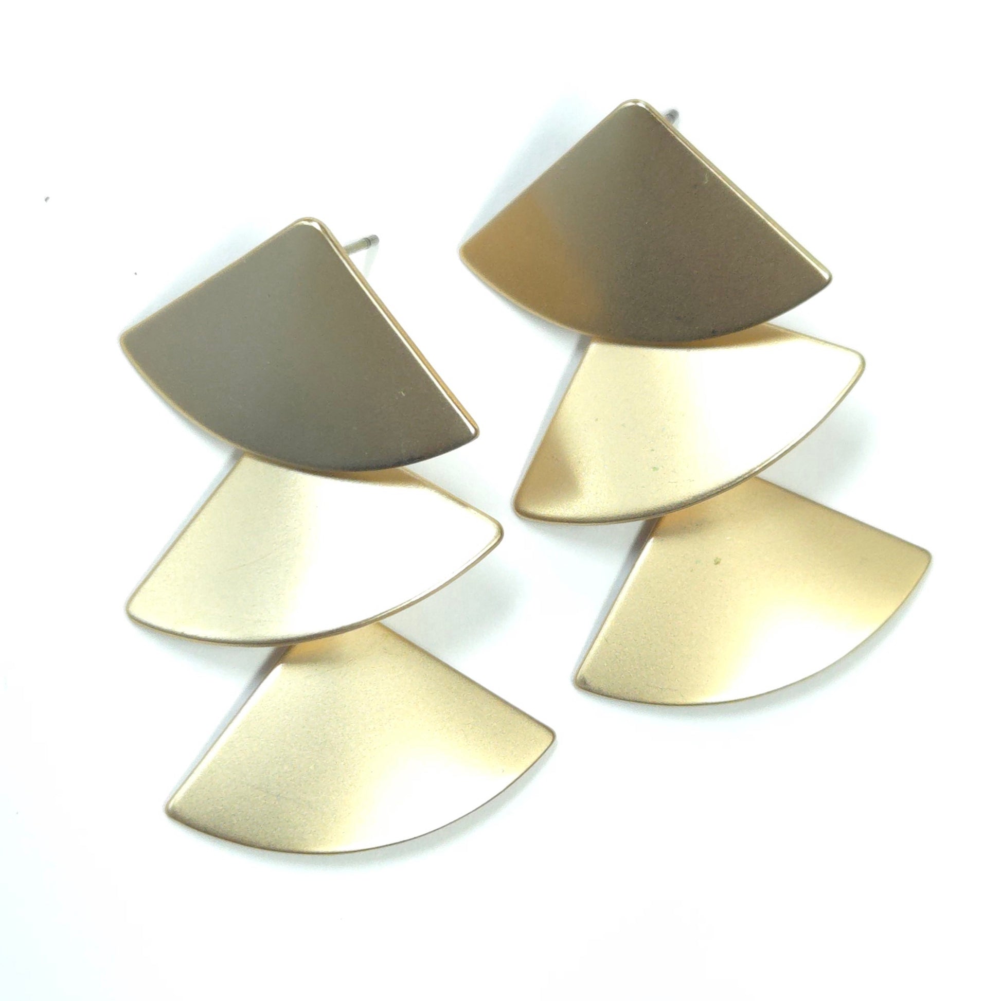 Pair of gold earrings with layered fan-shaped design on a white background