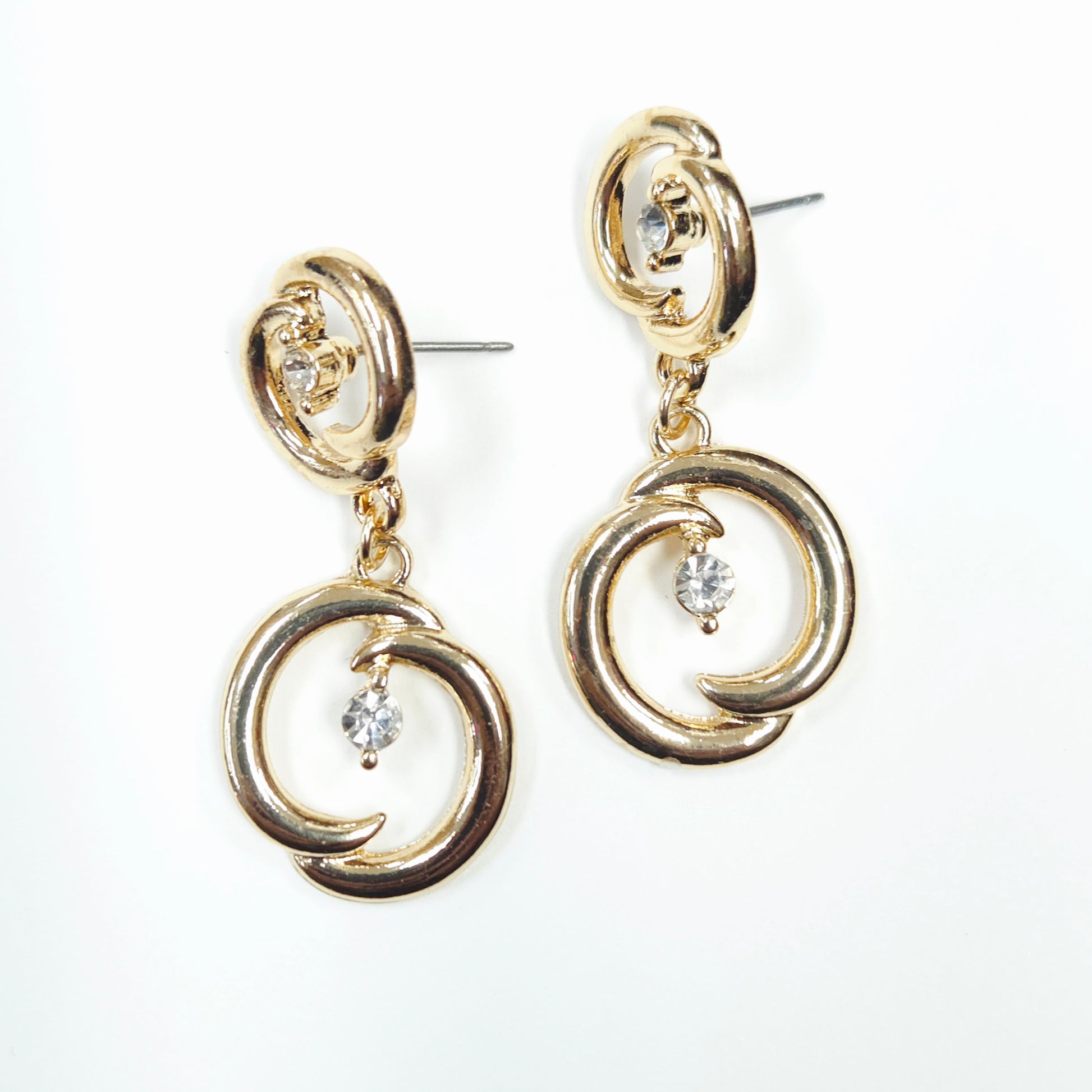 Gold earrings with circular design and small crystals on a white background