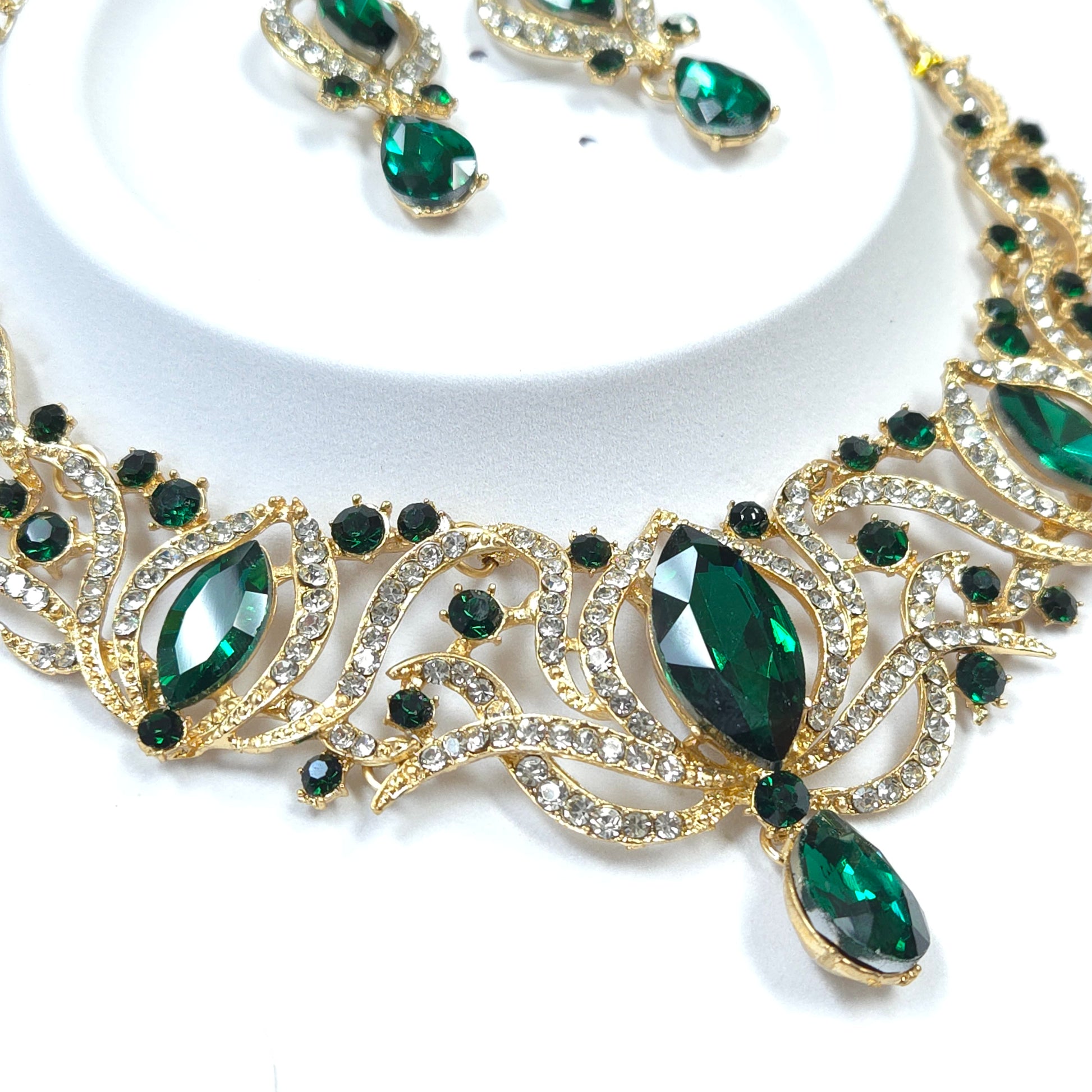 Gold necklace with green gemstones on a white background