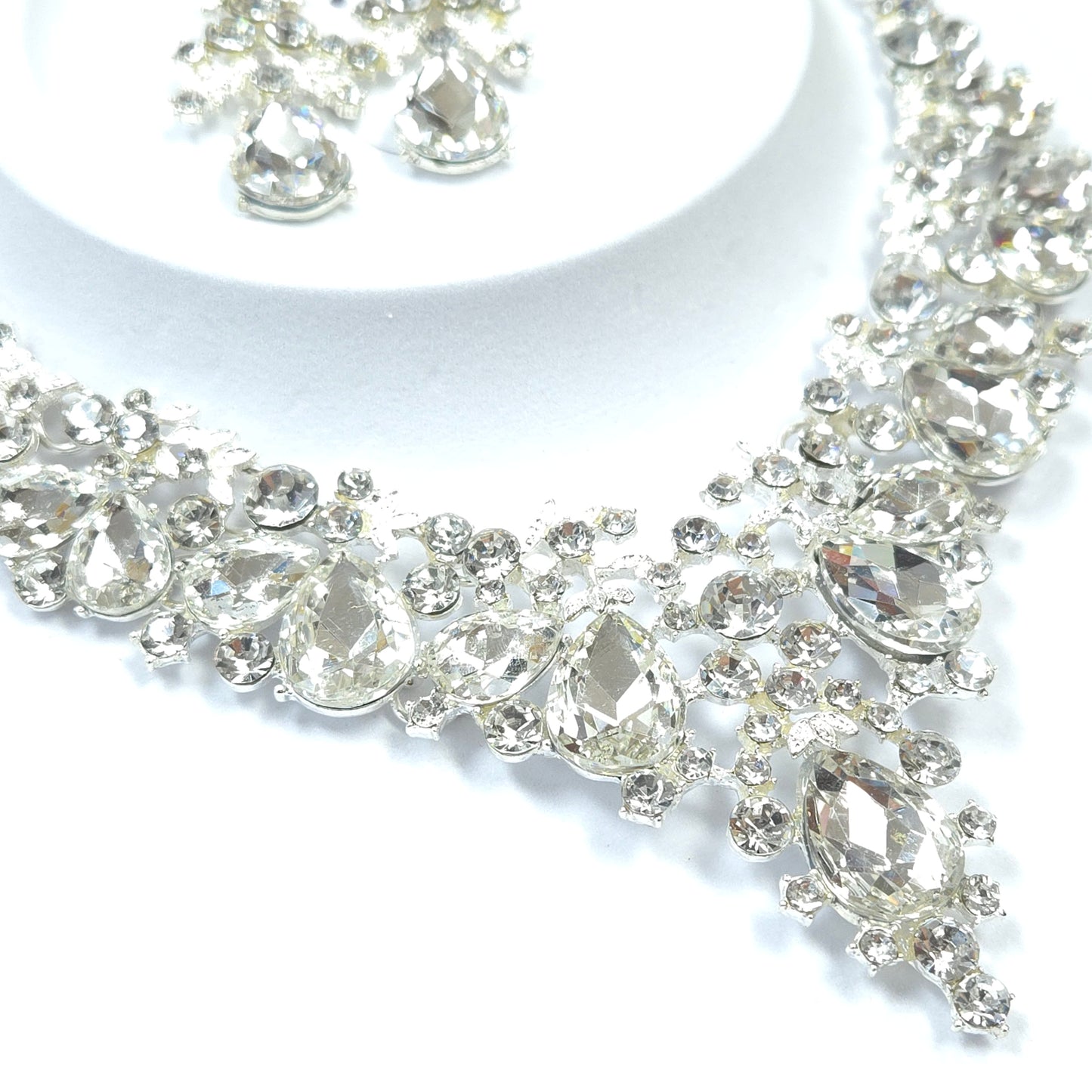Close-up of a silver earring with clear gemstones on a white background
