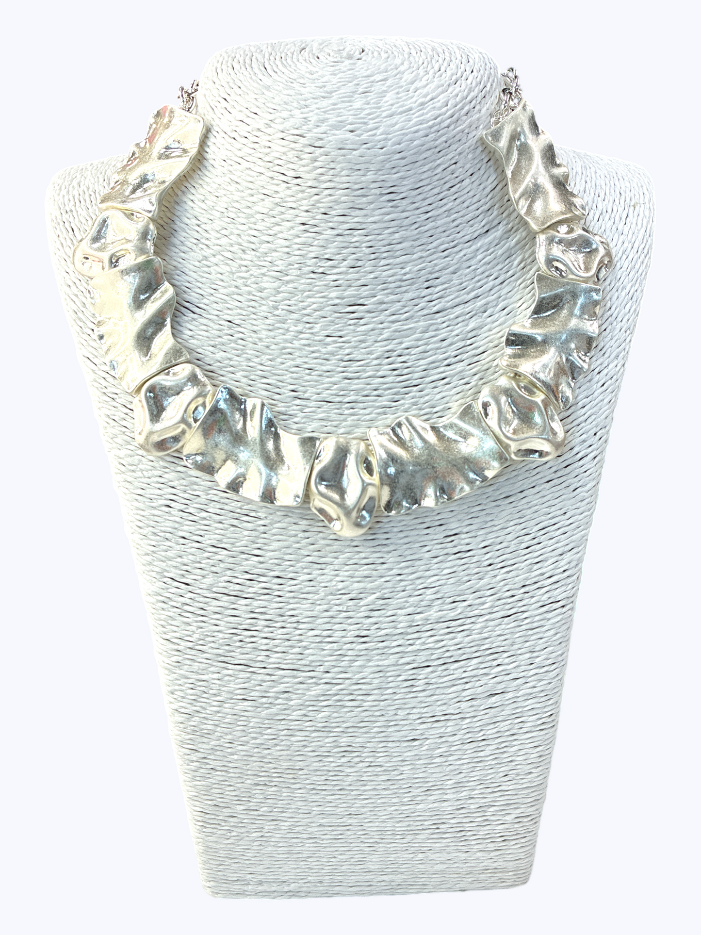 Silver necklace on a textured white stand