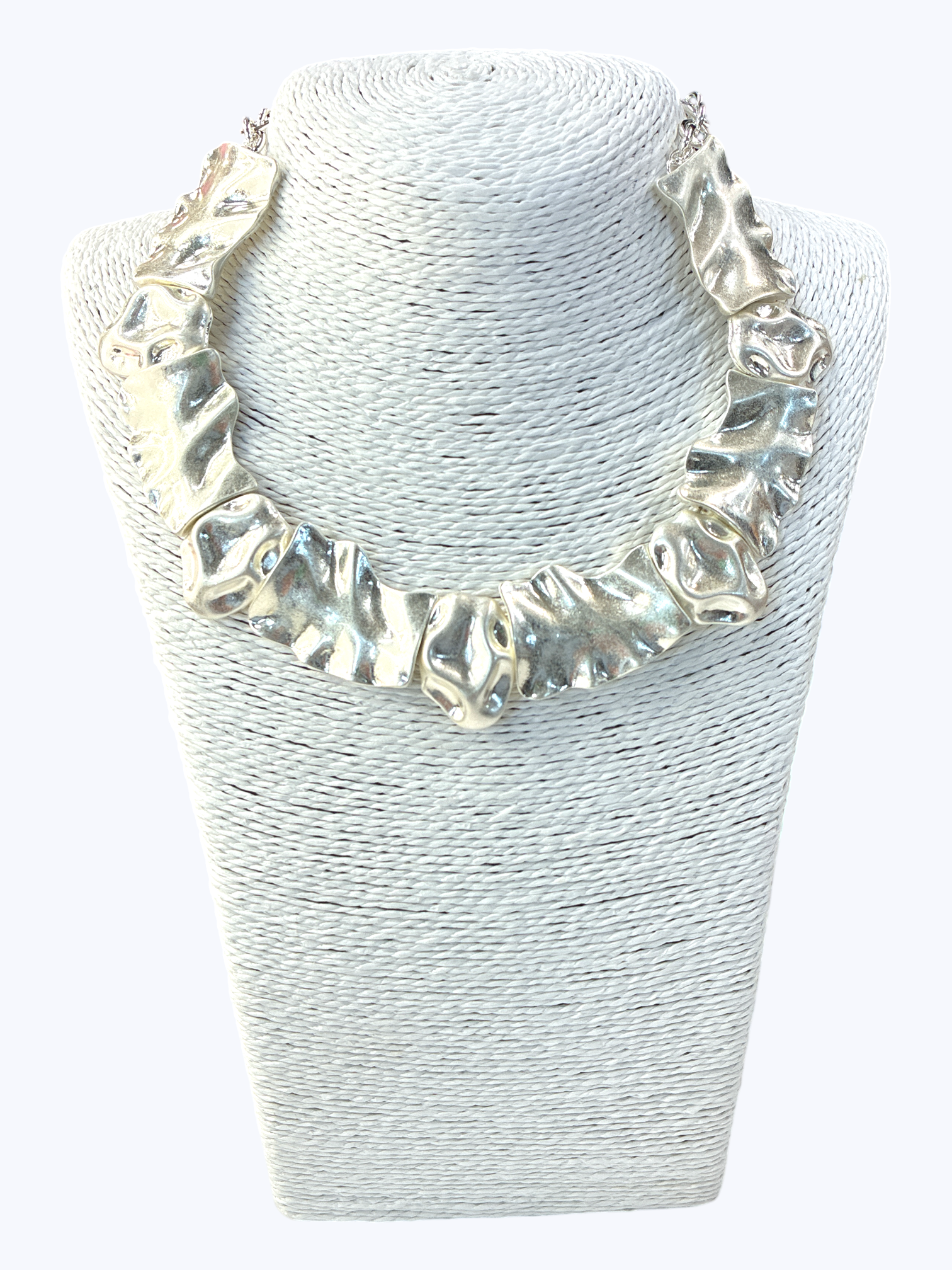 Silver necklace on a textured white stand