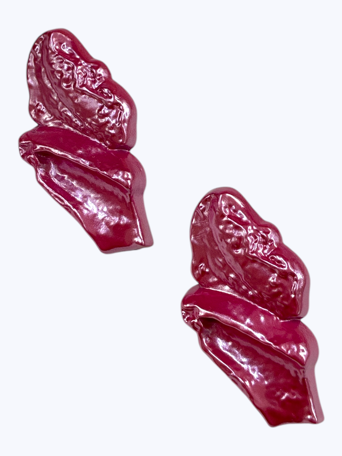 Glossy abstract statement earrings with sculpted magenta resin design for a bold modern boutique look.