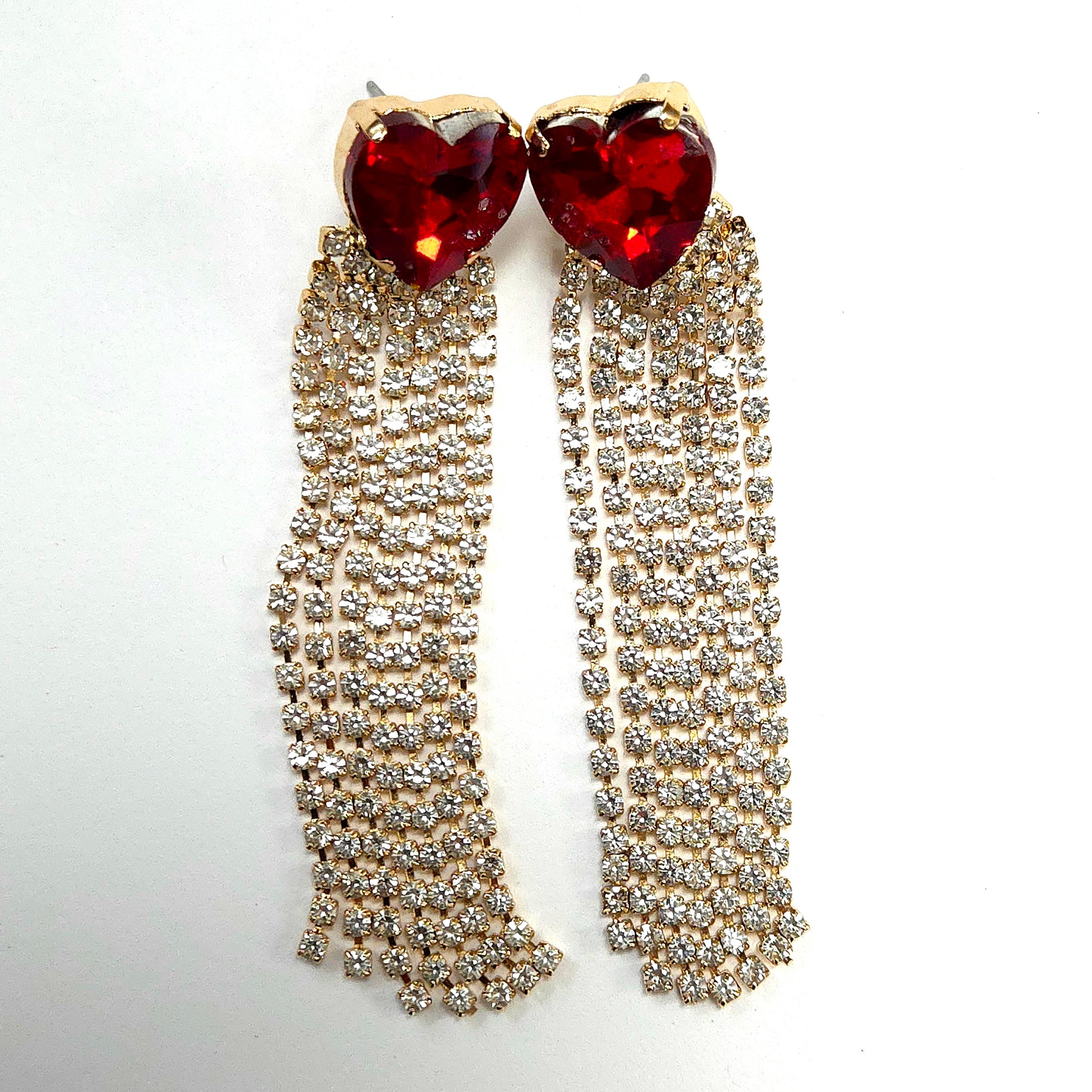 Earrings with red heart-shaped stones and gold fringe on a white background
