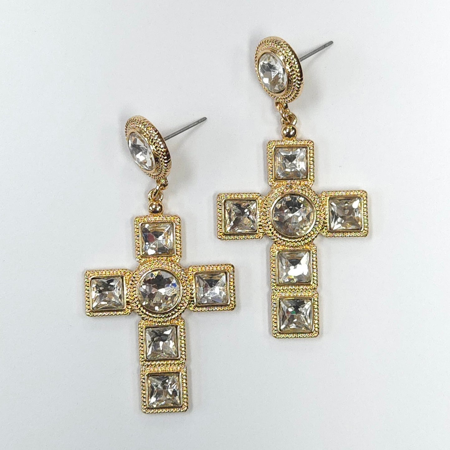 Gold cross-shaped earrings with crystal-like stones on a white background
