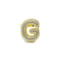 Gold letter 'G' brooch with gemstones on a white background