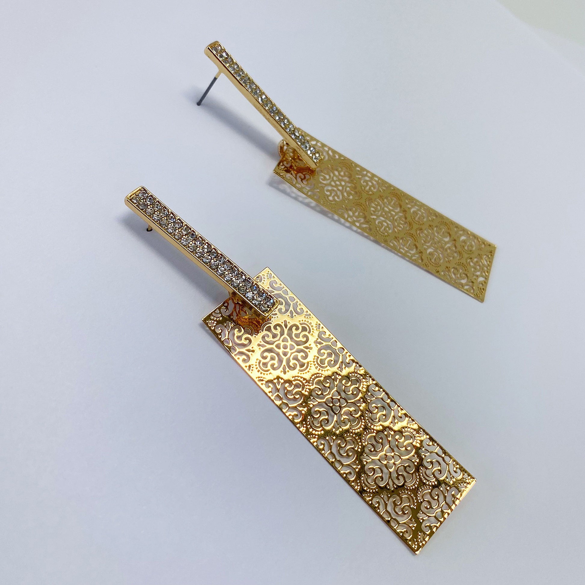 A pair of gold earrings on a white background