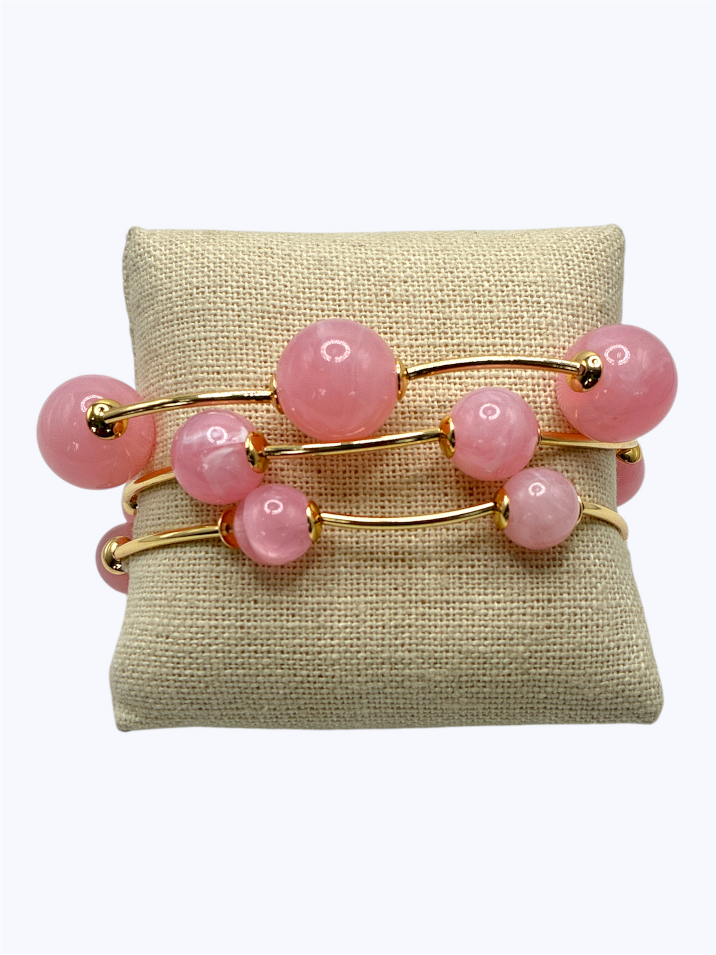Elegant beaded stretch bracelet set with glossy round beads and gold-tone curved bar accents displayed on linen cushion for boutique fashion accessories collection