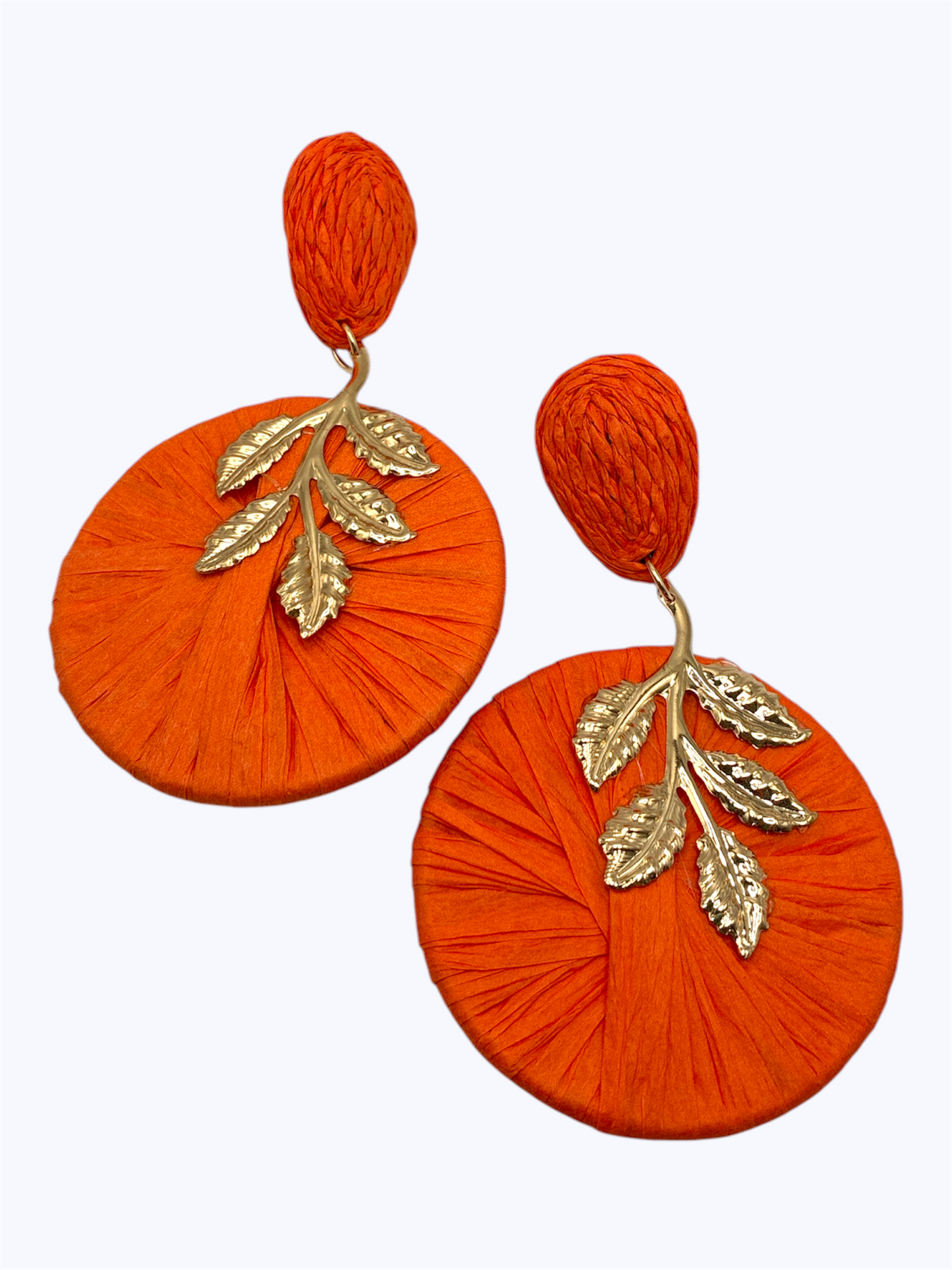 Oversized raffia disc drop earrings featuring woven circular detailing with gold tone leaf accents and textured stud tops.