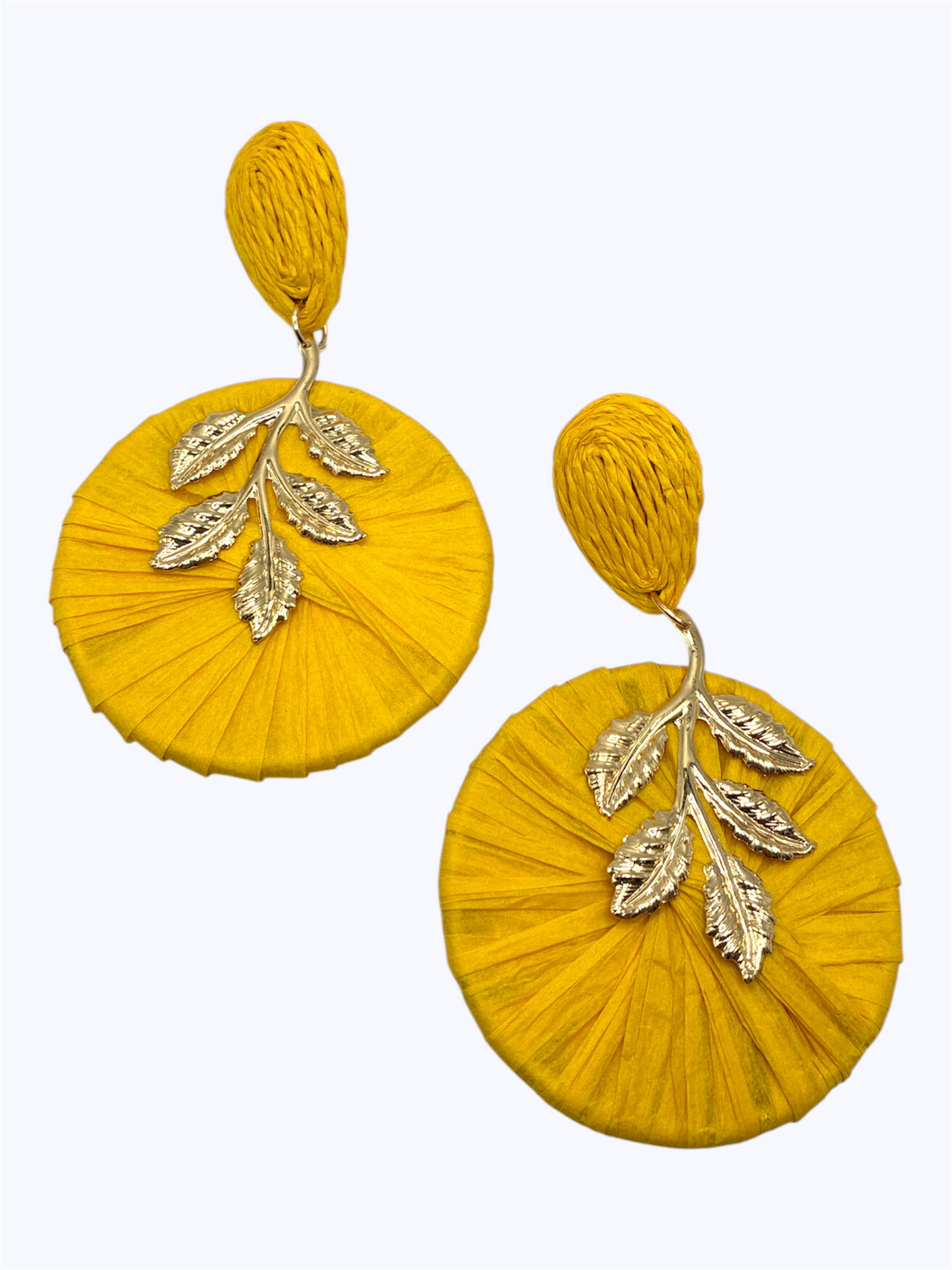 Oversized raffia disc drop earrings featuring woven circular detailing with gold tone leaf accents and textured stud tops.