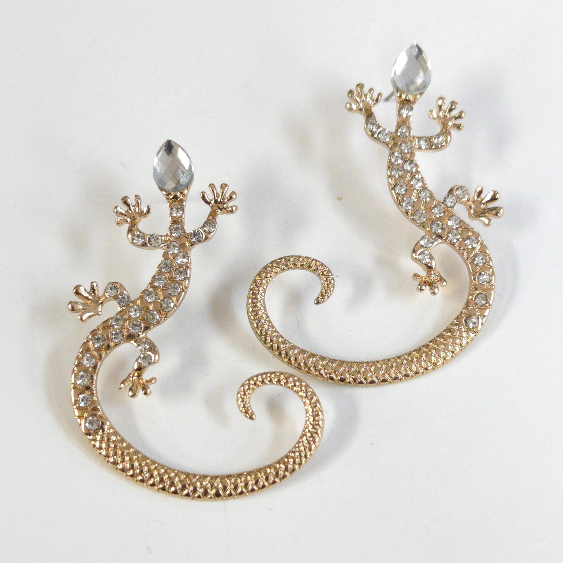 Gold lizard-shaped earrings with rhinestones on a white background