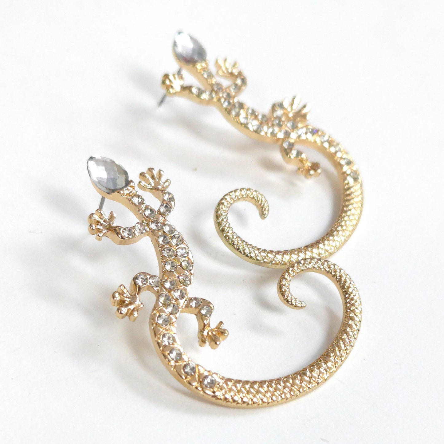 Gold lizard-shaped earrings with clear gemstones on a white background