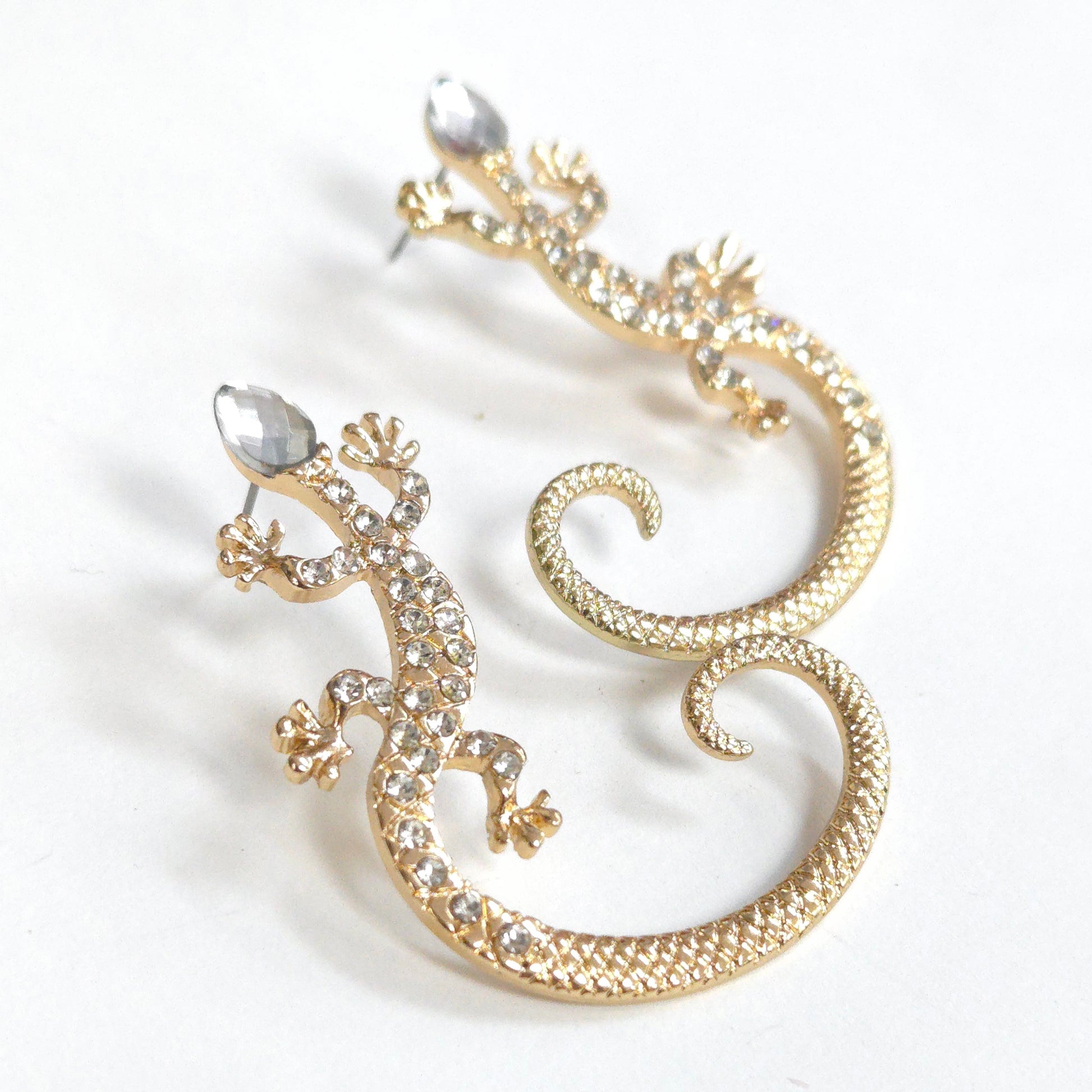 Gold lizard-shaped earrings with clear gemstones on a white background