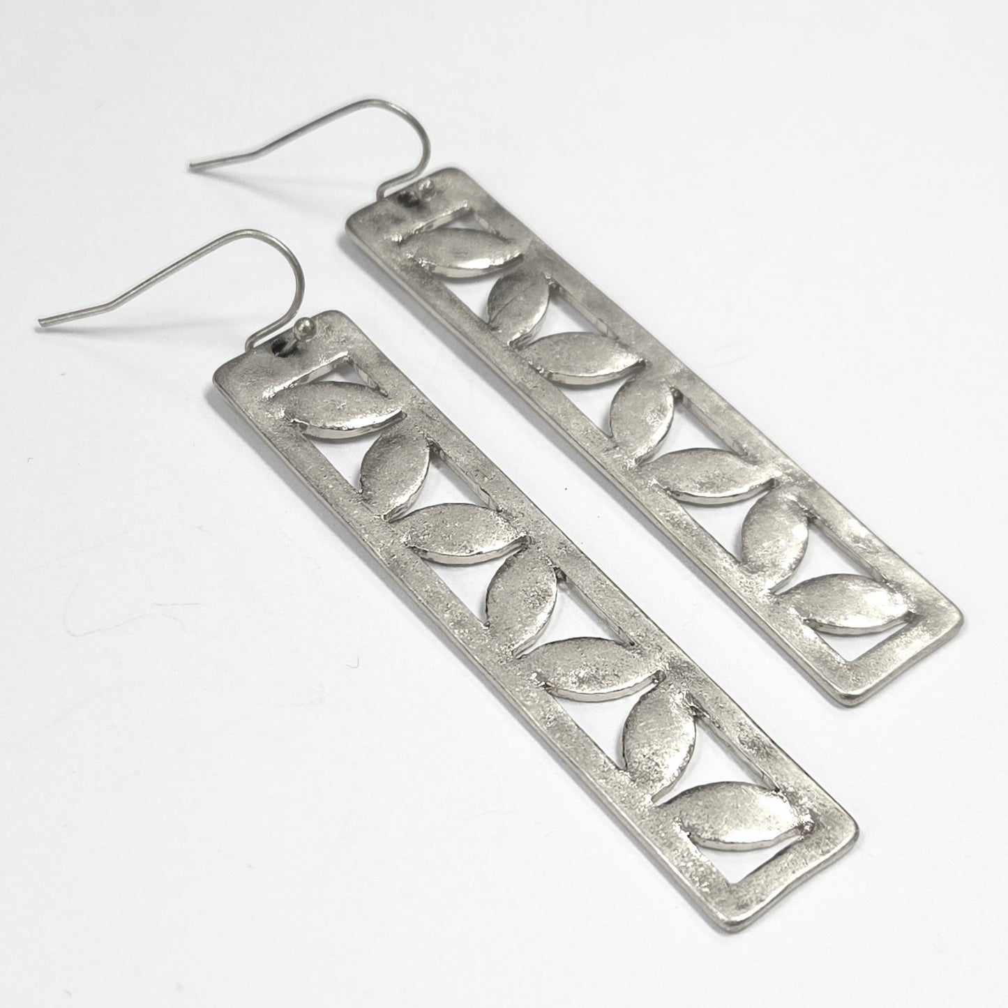 Pair of silver leaf-patterned earrings on a white background