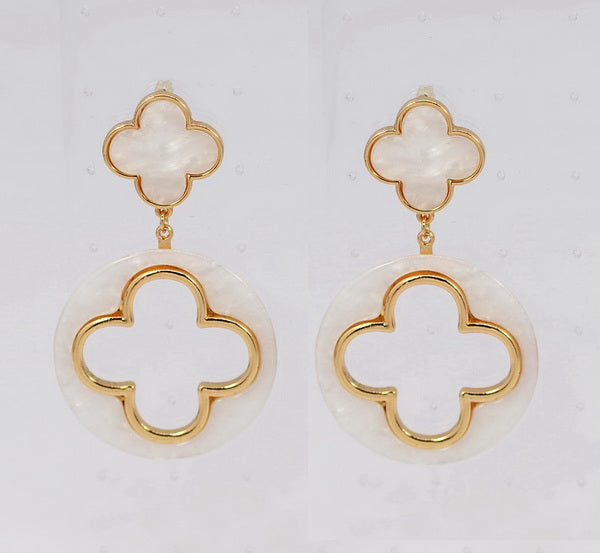 Pair of gold and white clover-shaped earrings on a light gray background