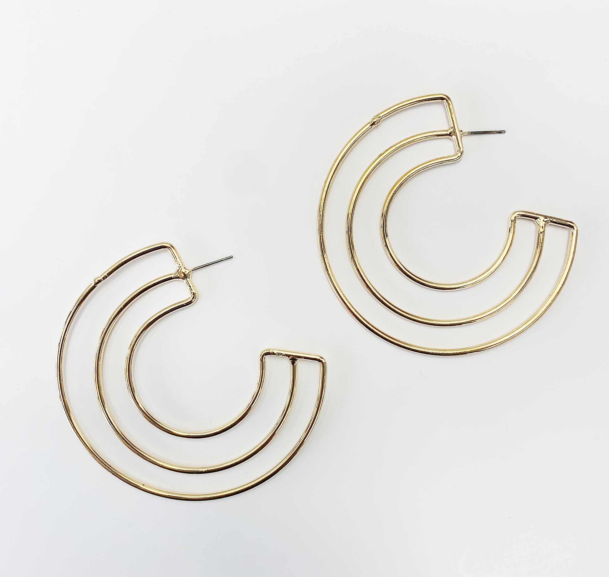 A pair of gold-colored hoop earrings with a geometric retro design, displayed against a white background.
