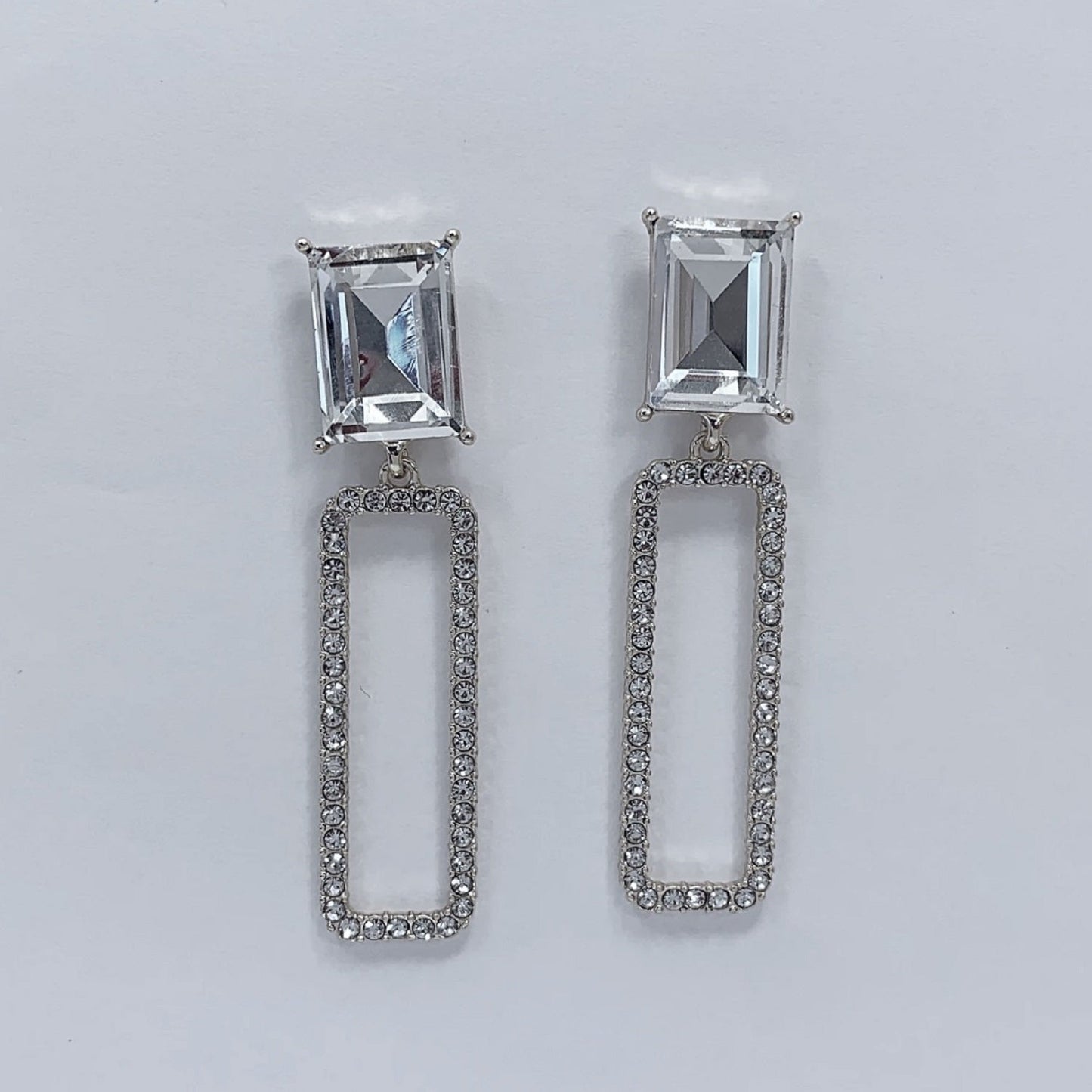 A collage of images showing a pair of rectangular-shaped dangle earrings with rhinestone embellishments. The earrings are displayed on a mannequin head and also shown from different angles to highlight their design and sparkle.