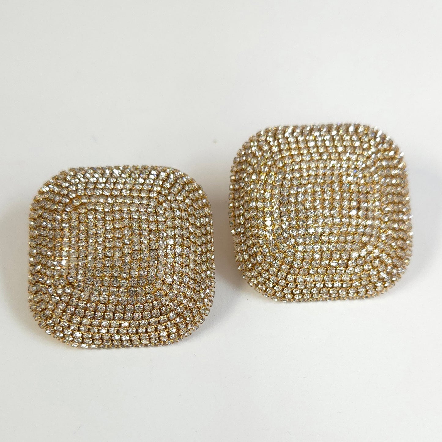 Pair of square-shaped gold earrings on a white background