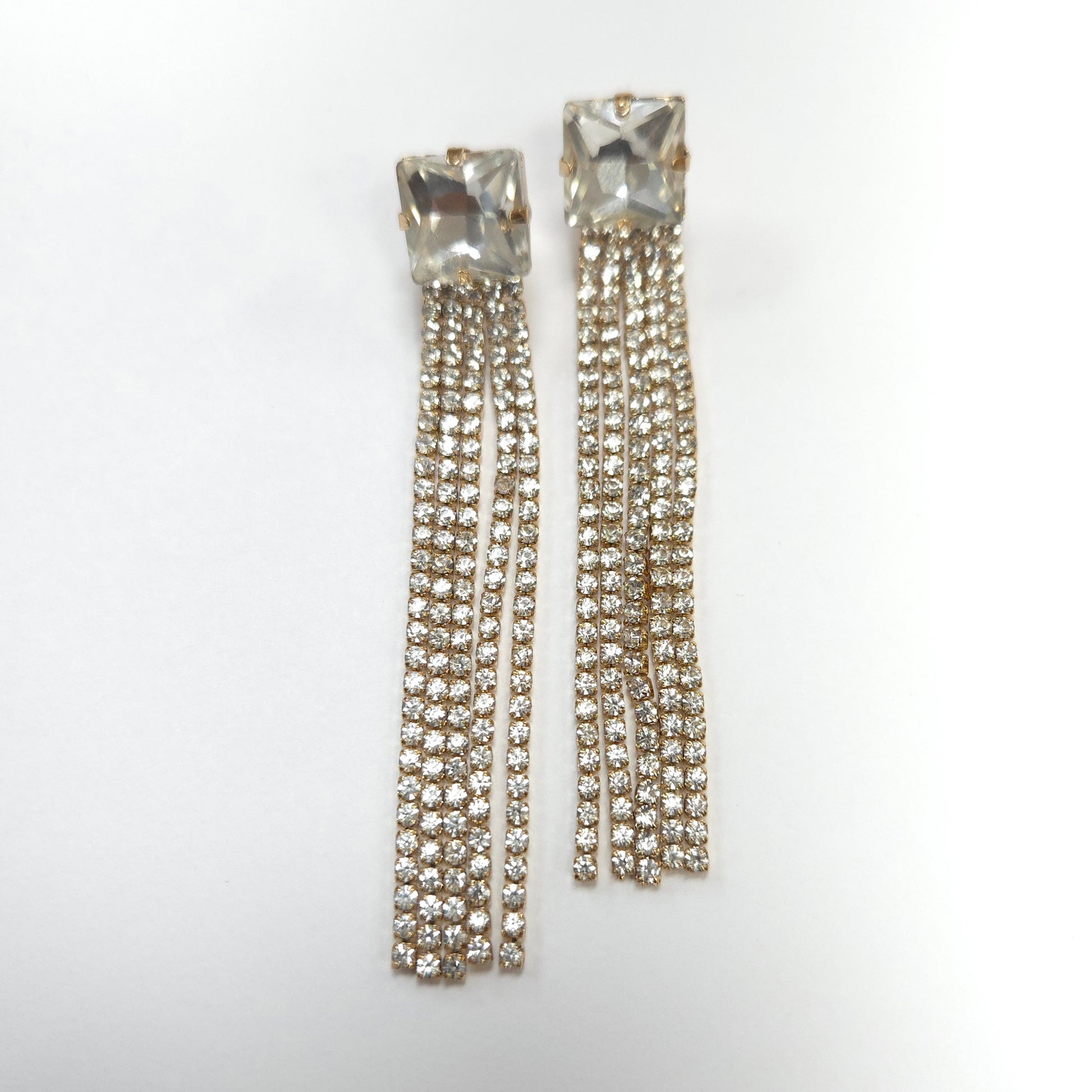 Pair of crystal earrings with dangling chains on a white background