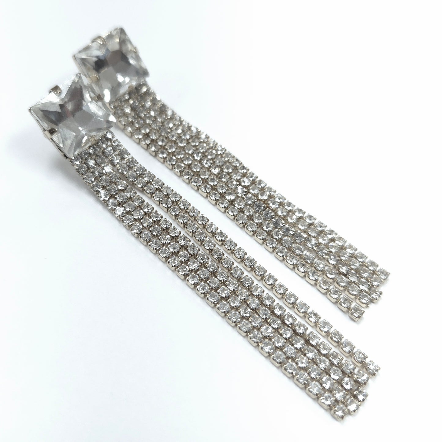 Silver tassel earrings with clear gemstones on a white background