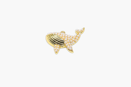 Gold and pearl whale-shaped brooch on a white background