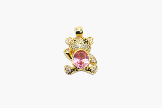Gold teddy bear pendant with a pink gem on a white background