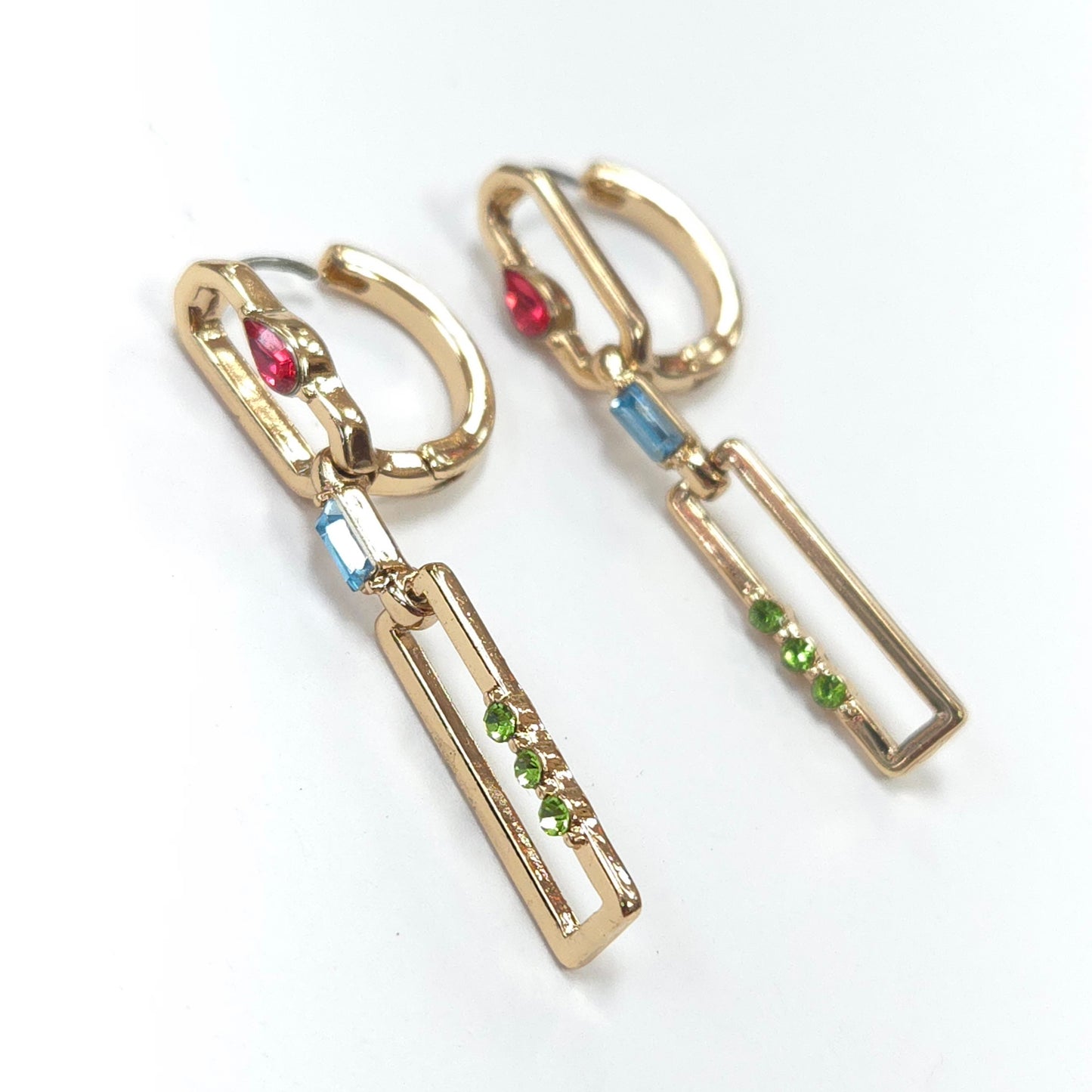 Gold earrings with colorful gemstones on a white background
