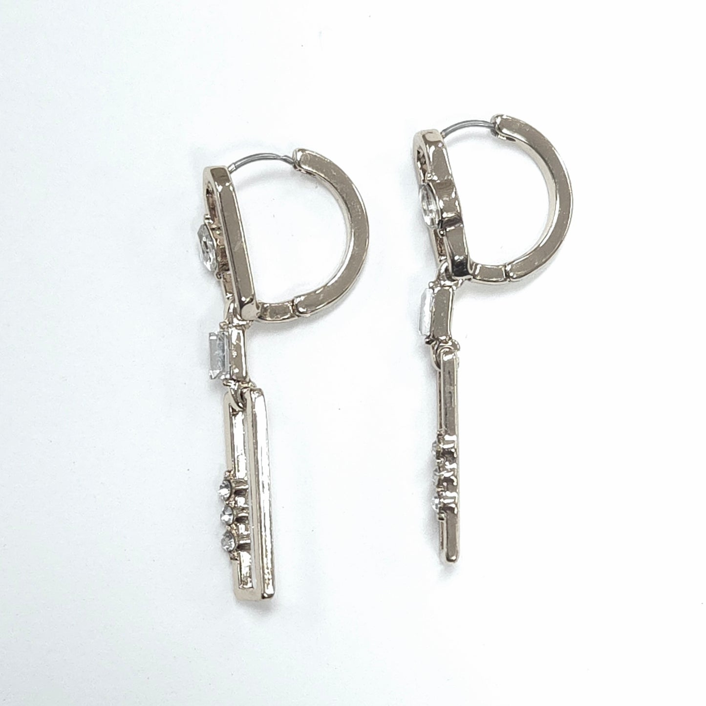 Pair of silver hoop earrings with key-shaped charms on a white background
