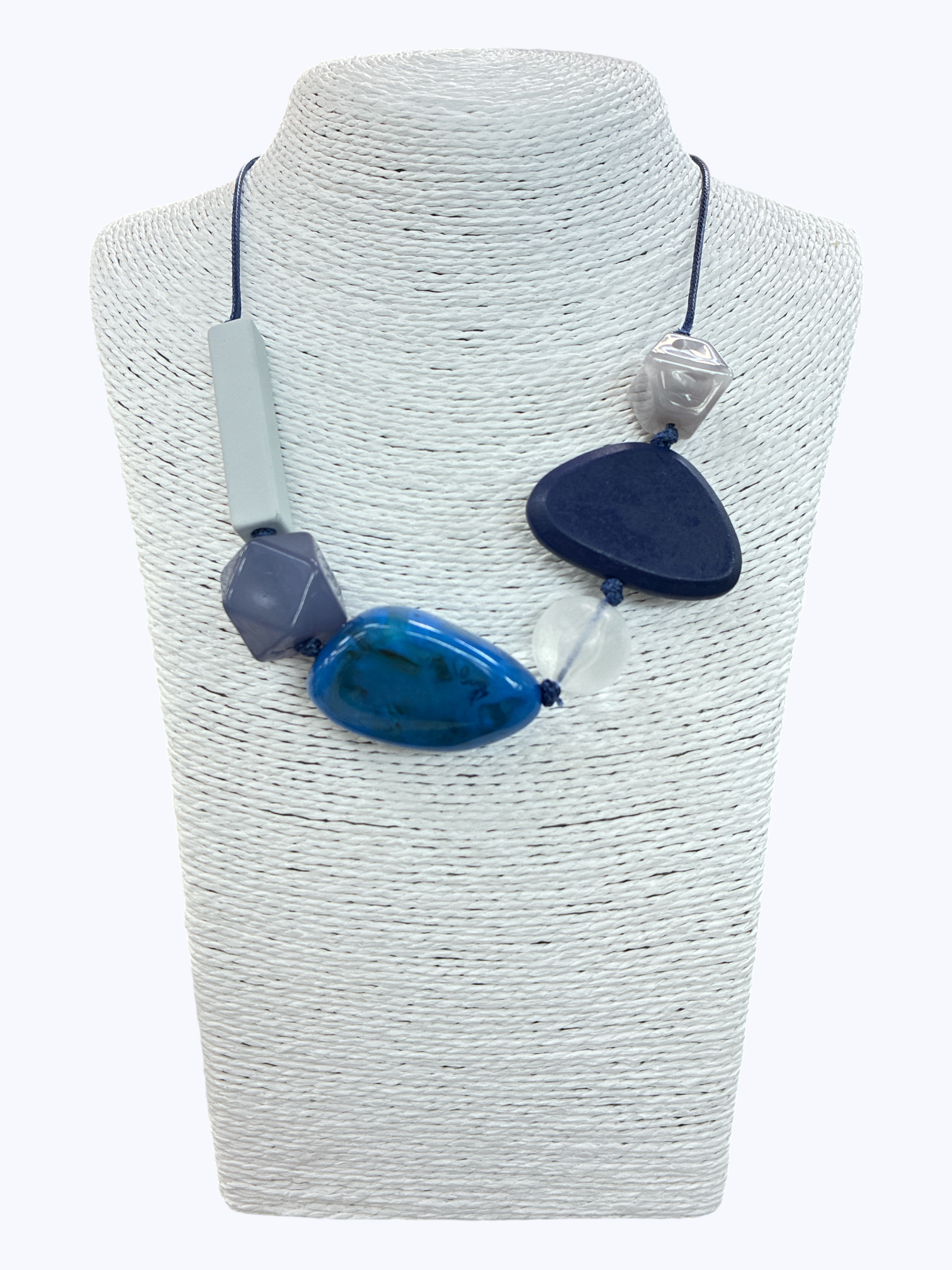 Blue geometric statement necklace with oversized mixed-shape beads and contemporary asymmetrical cord design on mannequin bust