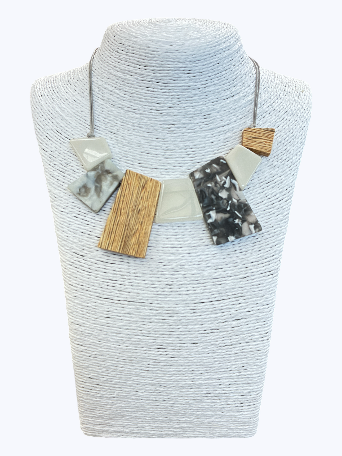 Abstract geometric statement necklace with gray marbled resin, wood-textured accents, and neutral shapes on cord for a contemporary boutique style.