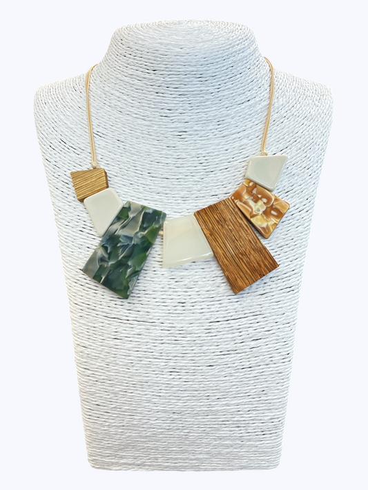 Abstract geometric statement necklace with green marbled resin, wood-textured accents, and neutral shapes on cord for a modern boutique-inspired look.