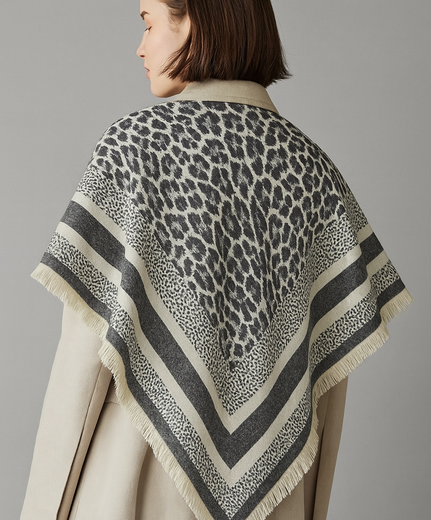 Person wearing a leopard print shawl over a beige coat on a gray background