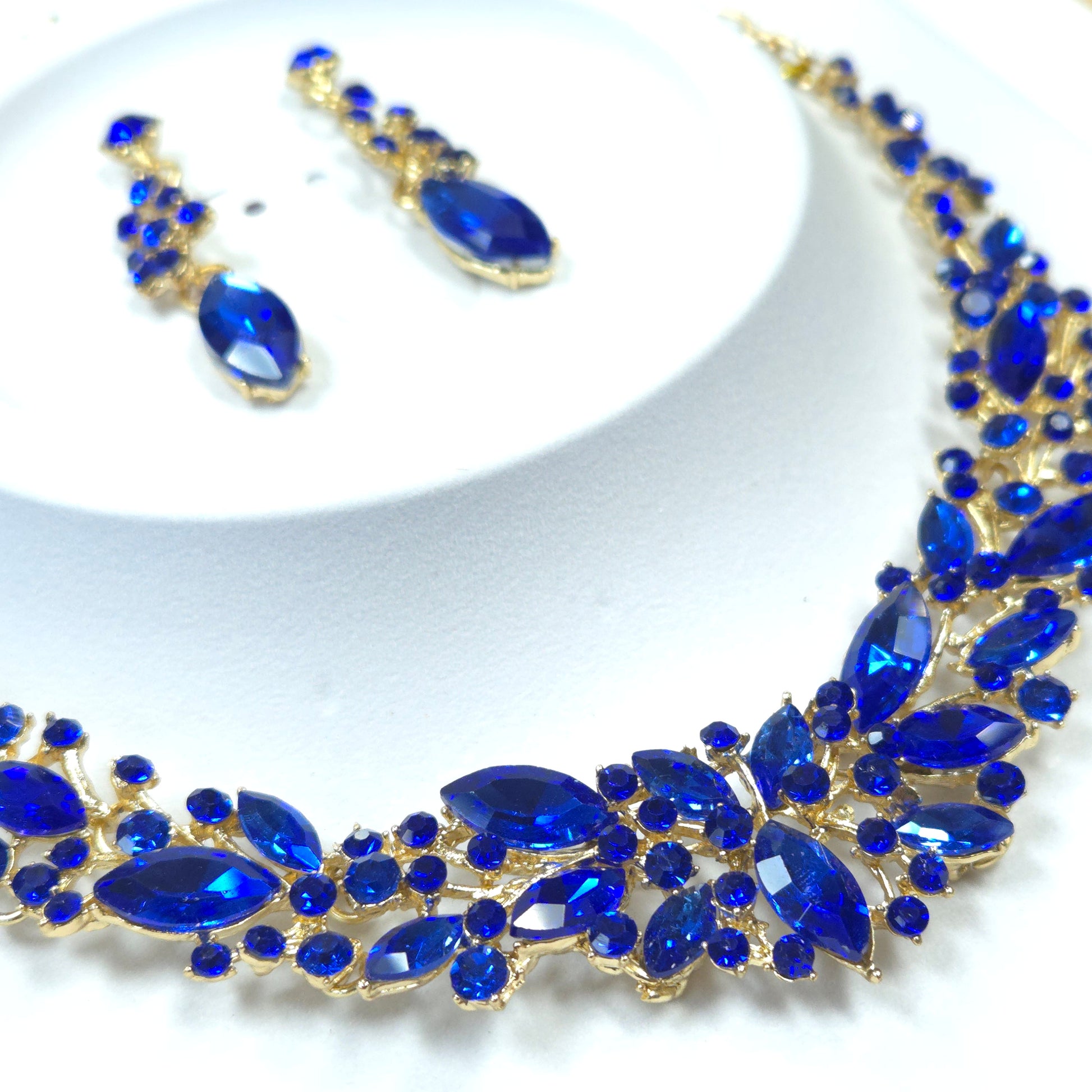 Jewelry set with blue gemstones and gold accents on a white background