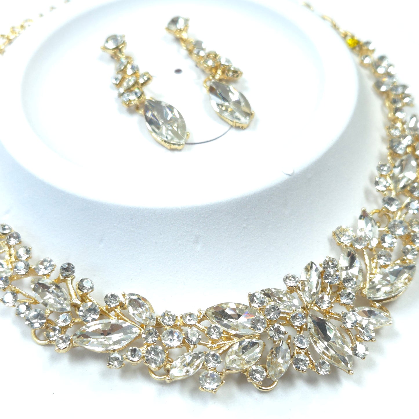 Gold and crystal bracelet with matching earrings on a white background