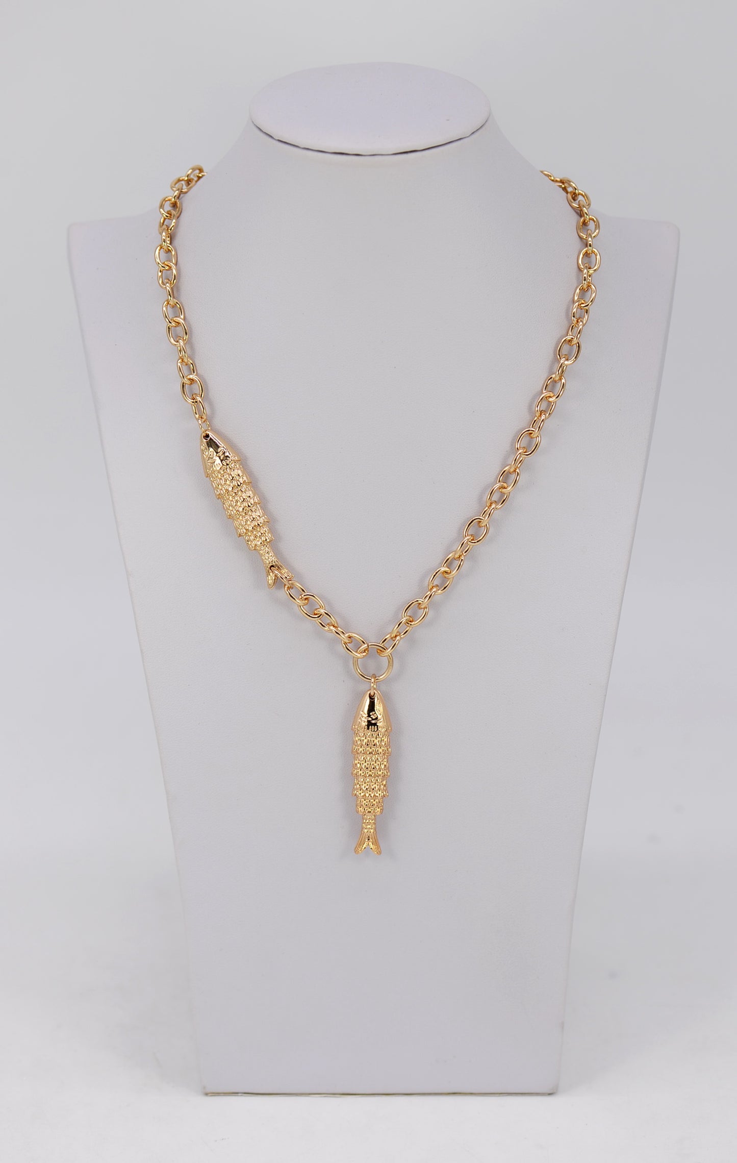Gold necklace with a fish pendant on a mannequin bust.